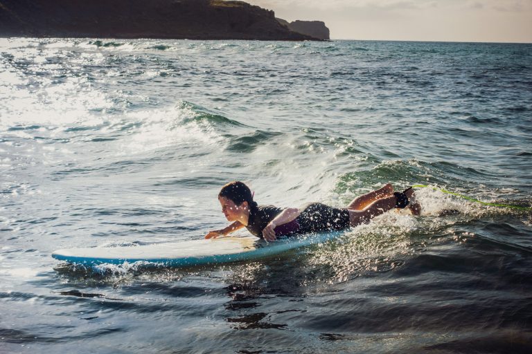 Kreeta, Kreikka, surffailu Teini-ikäinen nuori makaa surffilaudan päällä pienessä aallossa