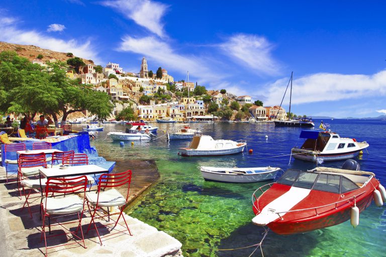 Rodos, Symi 2 Veneitä kelluu kirkkaassa vedessä terassikalusteisen tasanteen edessä.