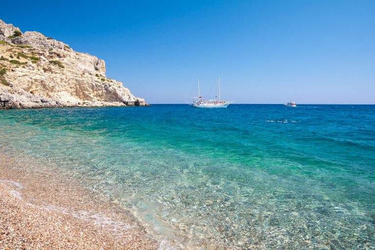 Rodos, Afandou 2 Purjelaiva ja moottorivene turkoosilla merellä kallion edustalla.