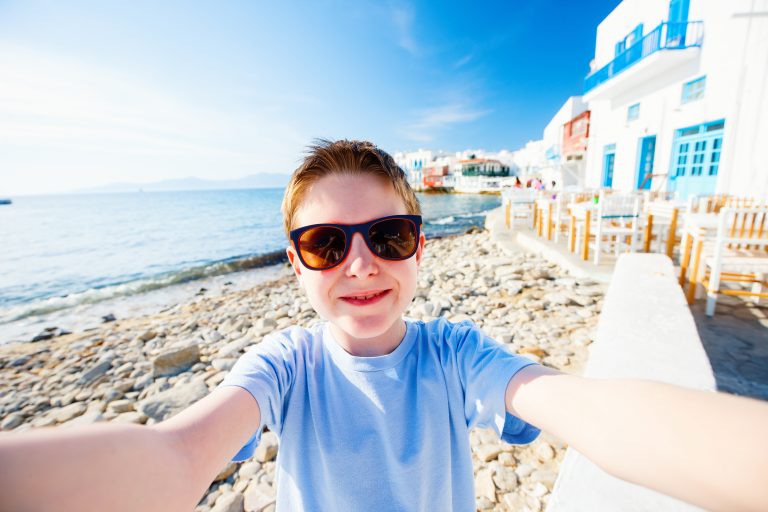 Kreikka, yleinen, perhe 5 Nuori poika ottamassa selfietä aurinkolasit päässä kreikkalaisella rannalla.