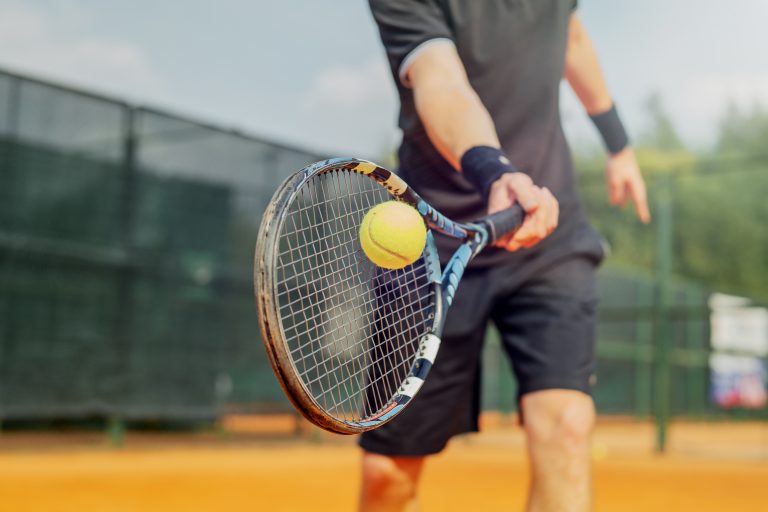 Aktiviteetit, Jurmala, tennis Lähikuva miehen kädessä olevasta tennismailasta, jolla lyömässä palloa.